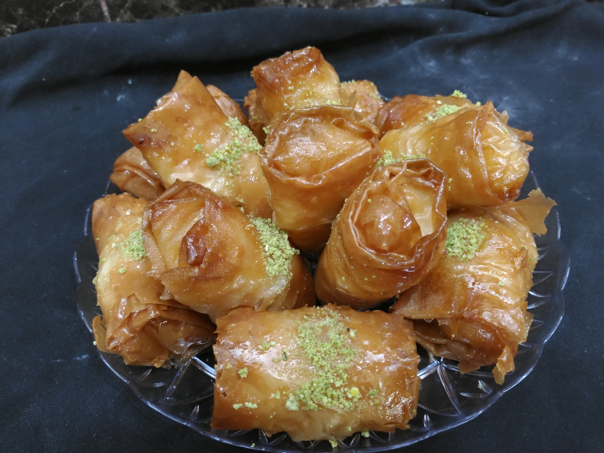 Rose-shaped baklava glistening with sweet syrup and dusted with ground pistachio