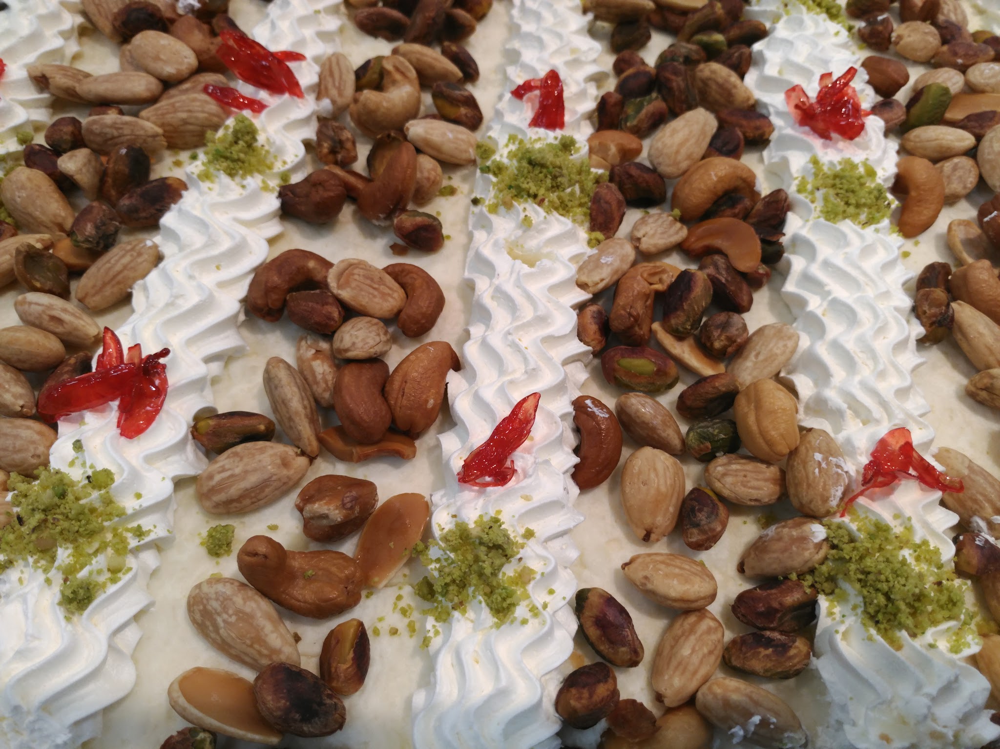 Traditional warbat pastries topped with almonds, pistachios, and candied cherries arranged on a cream base